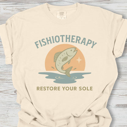 Beige t-shirt with 'Fishiotherapy' graphic and text on a wooden surface