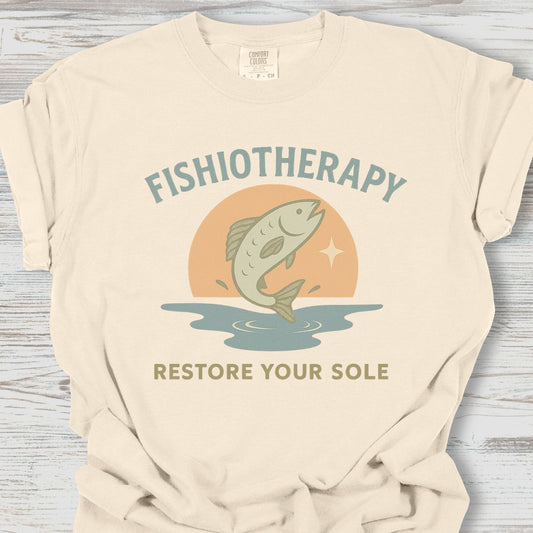 Beige t-shirt with 'Fishiotherapy' graphic and text on a wooden surface