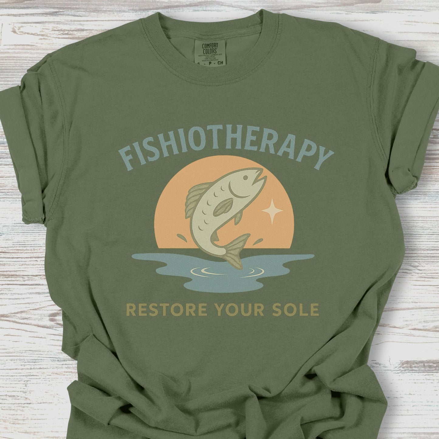 Green t-shirt with 'Fishiotherapy' graphic design on a wooden surface