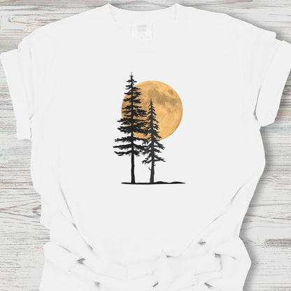 White t-shirt with a graphic of two trees and a full moon on a wooden surface