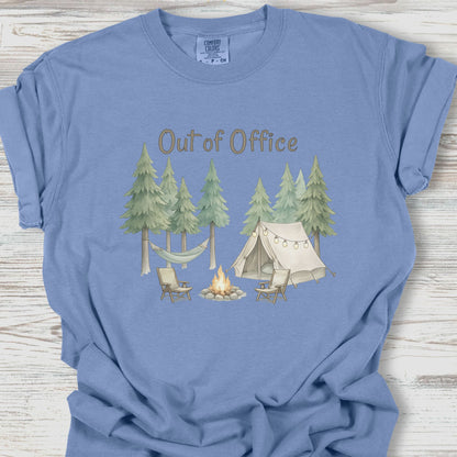 Blue t-shirt with camping graphic and 'Out of Office' text on a wooden surface