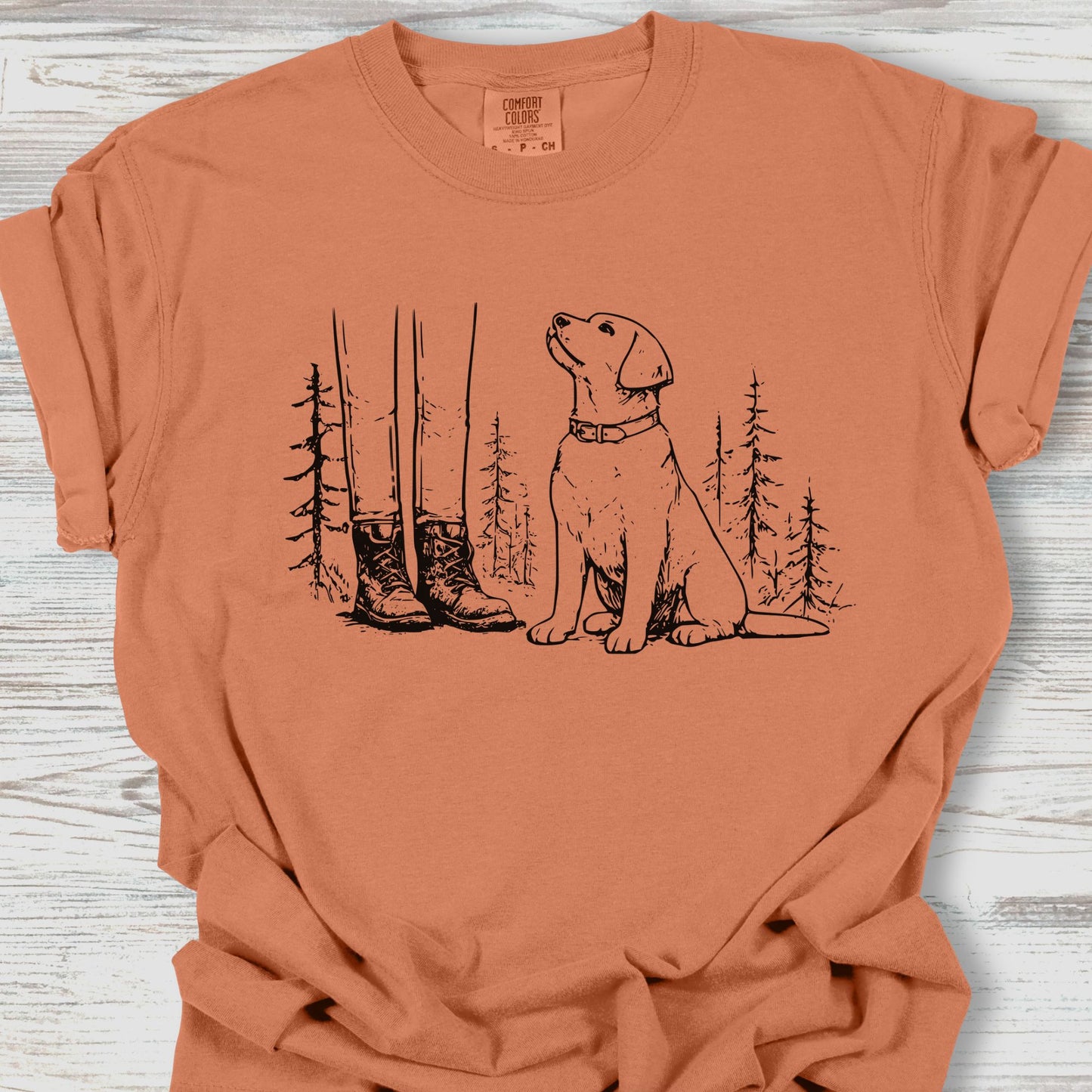 Coral t-shirt with a graphic of a dog and boots on a wooden surface