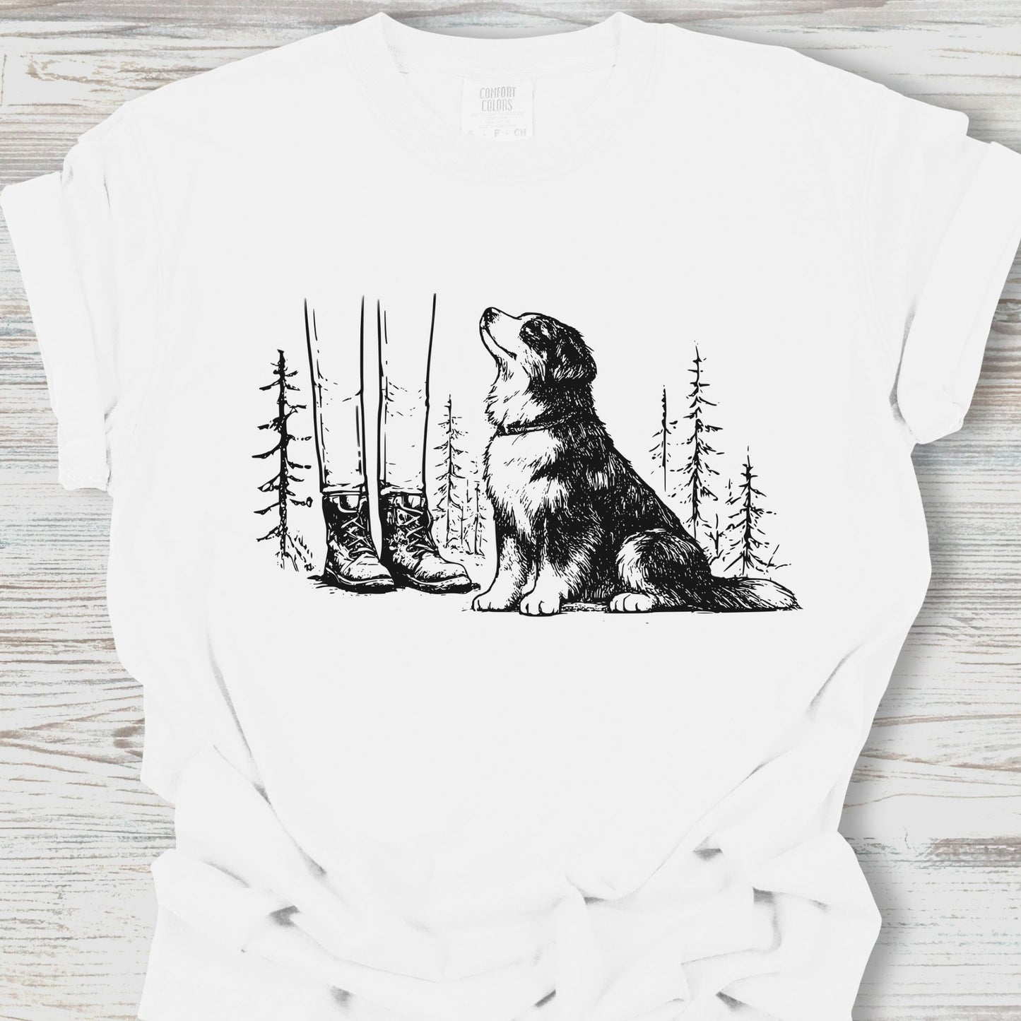 White t-shirt with a black and white illustration of a dog sitting in a forest on a wooden surface.