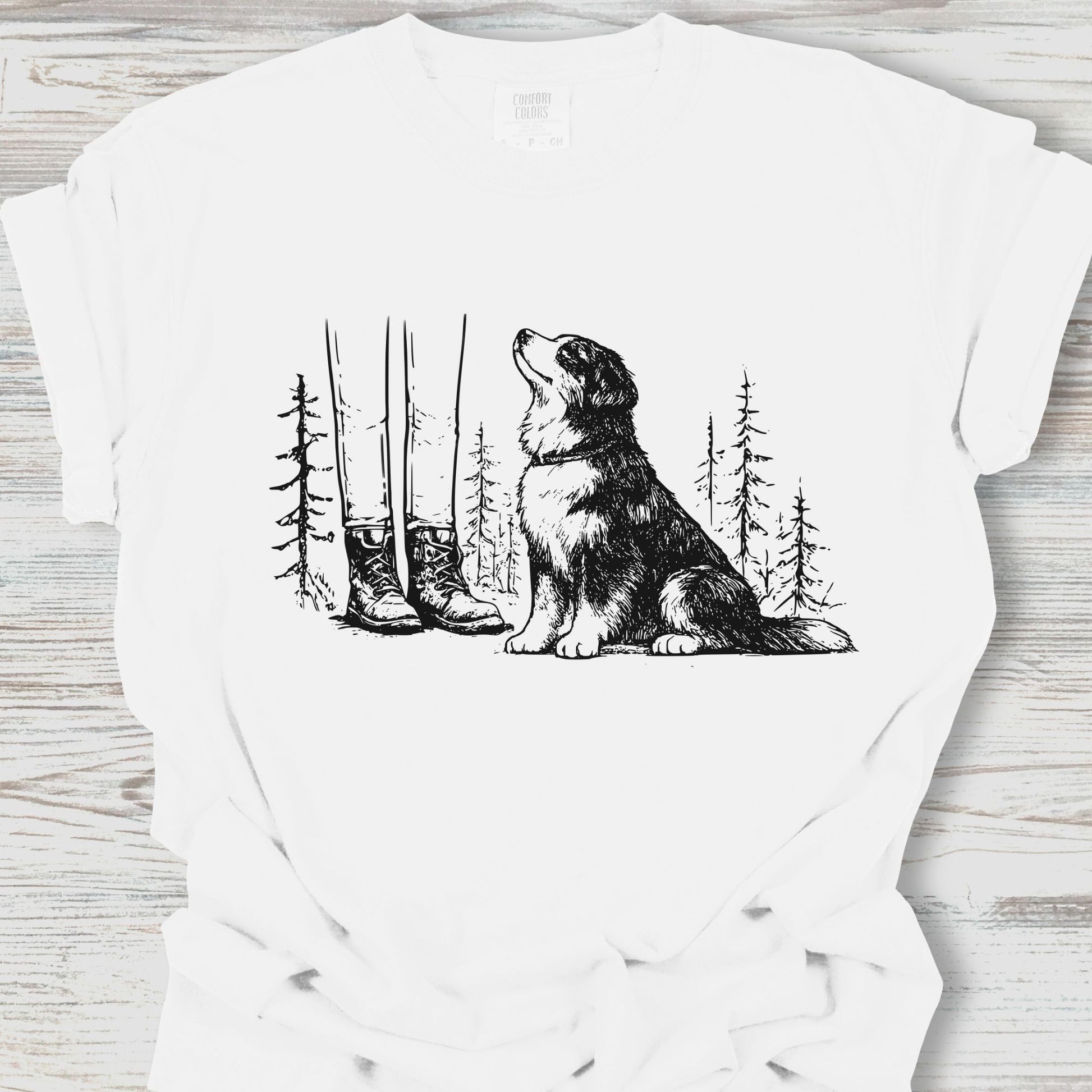 White t-shirt with a black and white illustration of a dog sitting in a forest on a wooden surface.