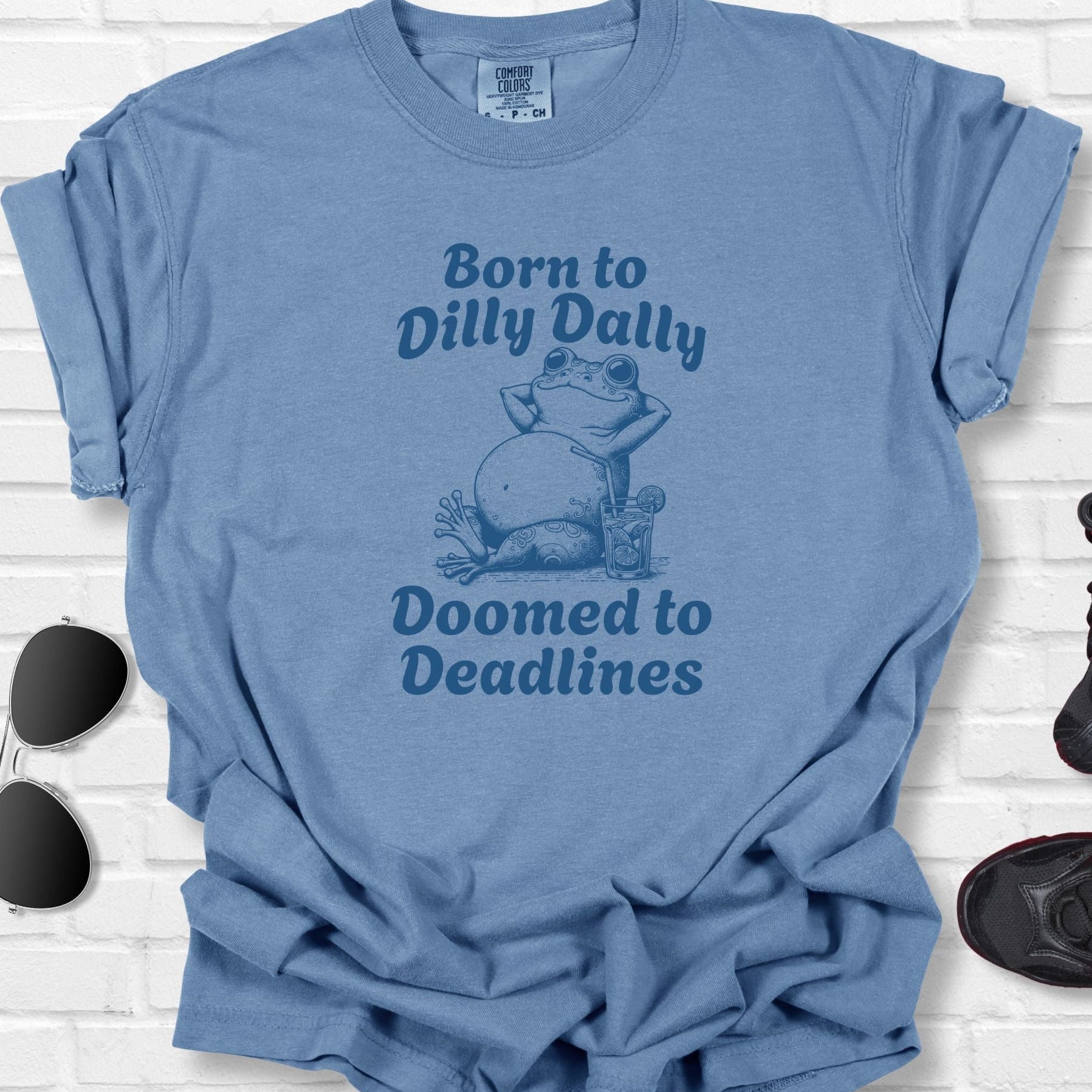 Blue t-shirt with a frog graphic and text on a white brick background