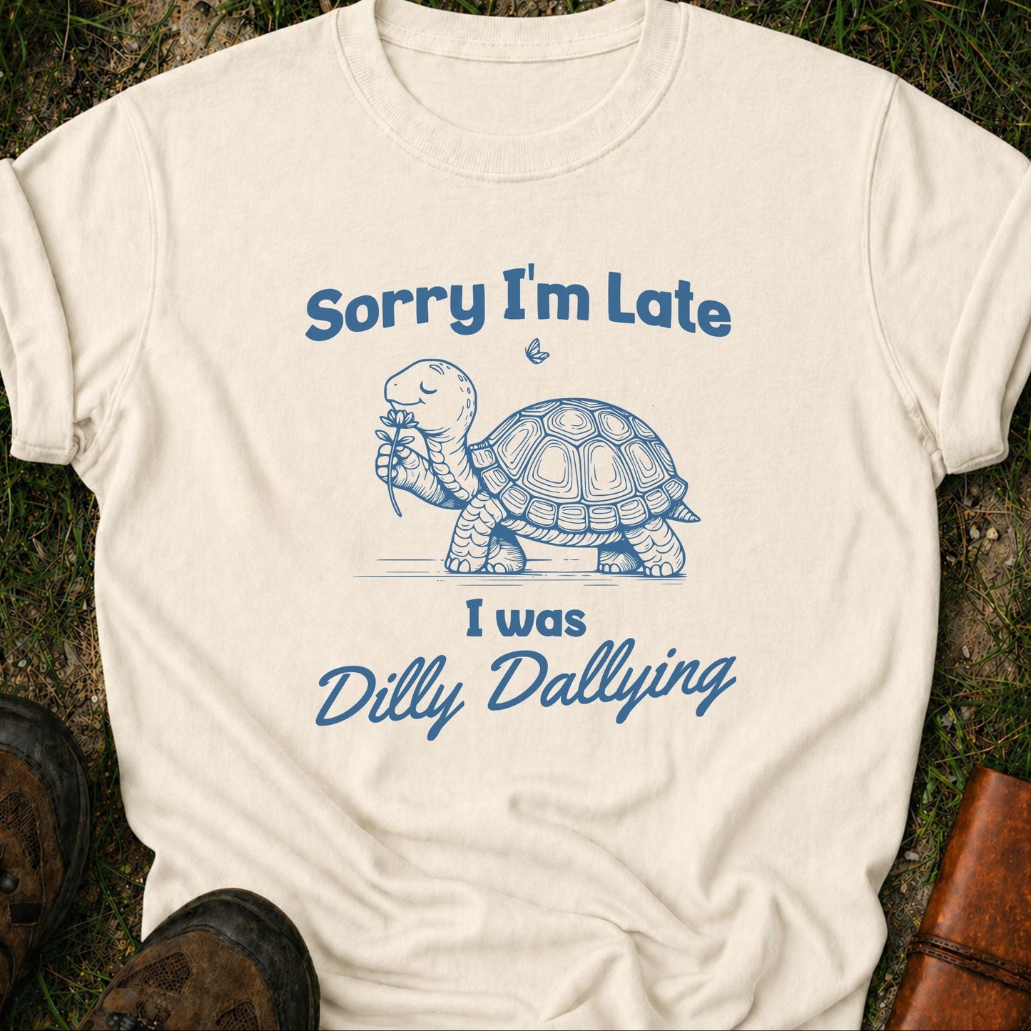 White t-shirt with blue turtle graphic and text on grass