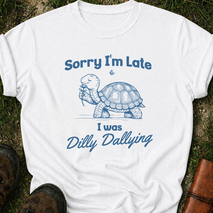 White t-shirt with blue turtle graphic and text on grass
