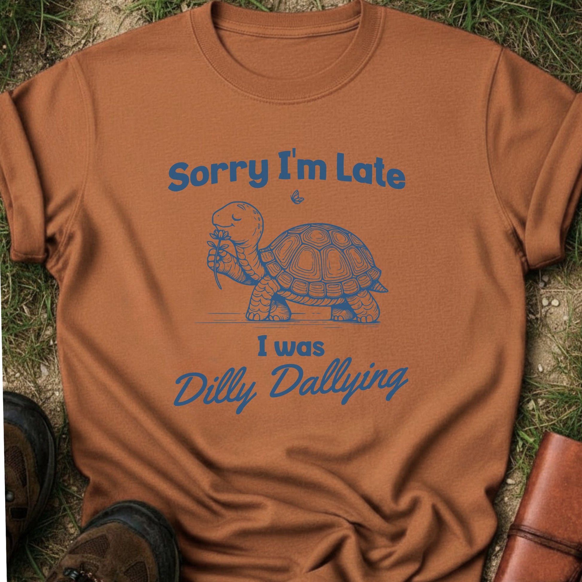 Brown t-shirt with a turtle graphic and text on grass