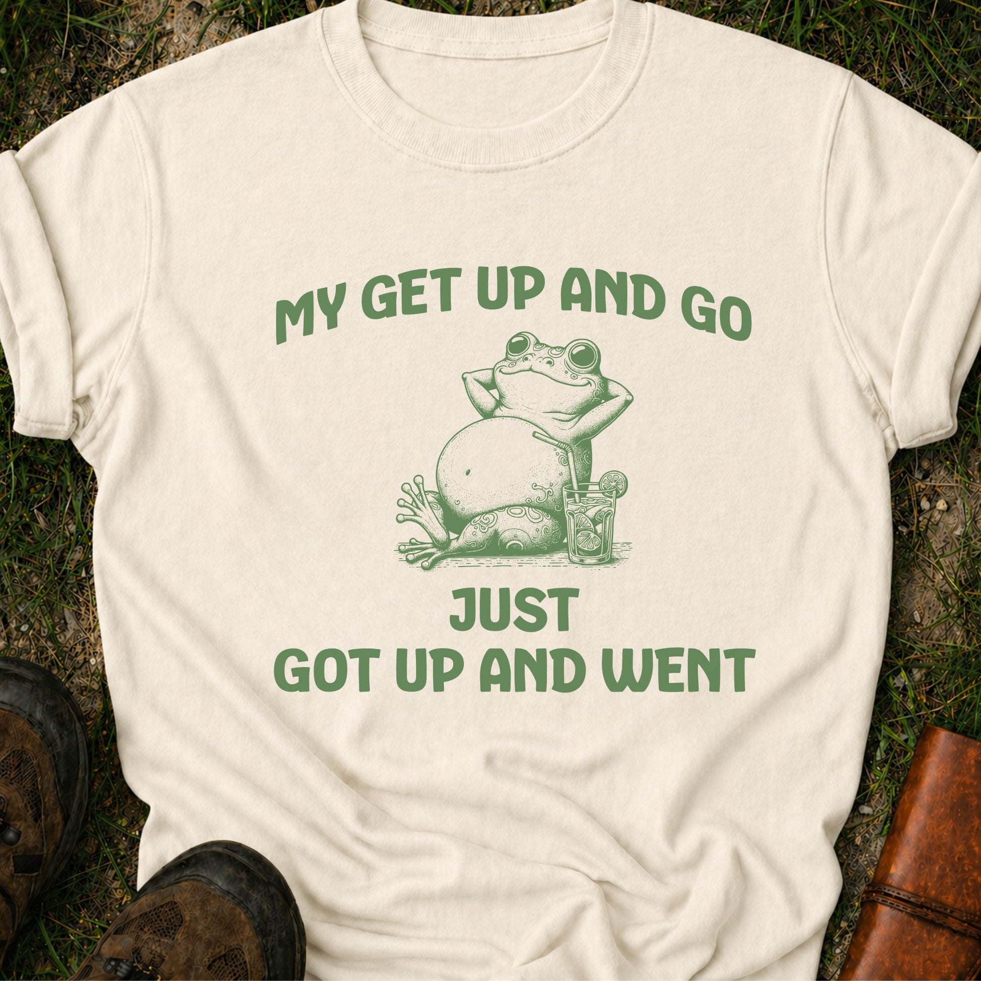 Beige t-shirt with a green frog graphic and text on grass