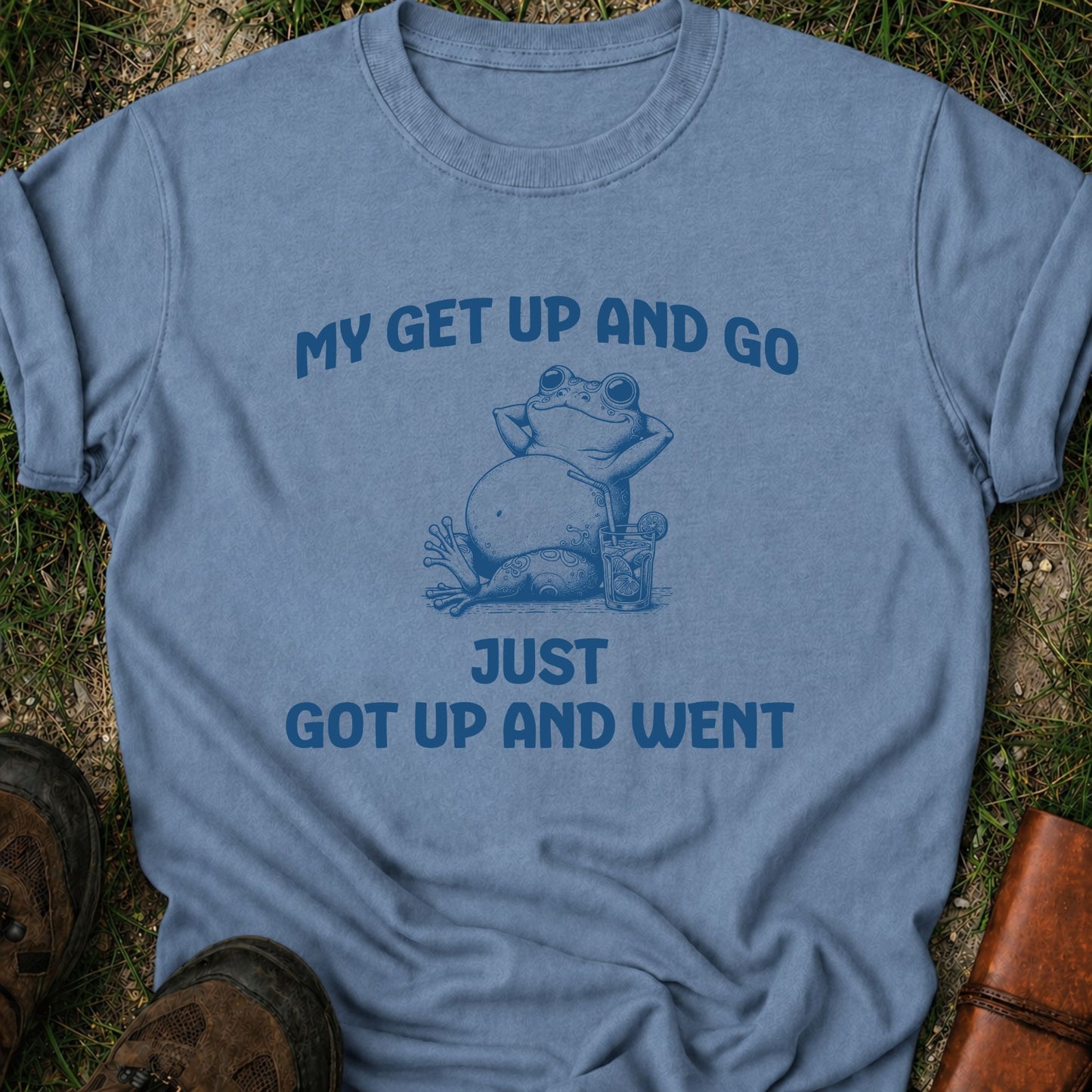 Blue t-shirt with a graphic of a frog and text on grass