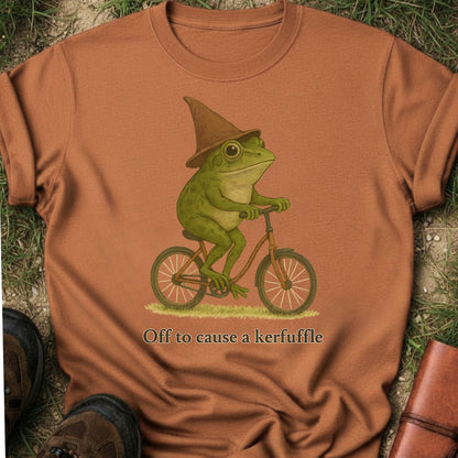 Orange t-shirt with a frog riding a bike graphic and text on grass.