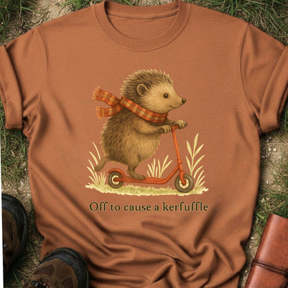 Orange t-shirt with a hedgehog on a scooter graphic and text 'Off to cause a kerfuffle' on grass.