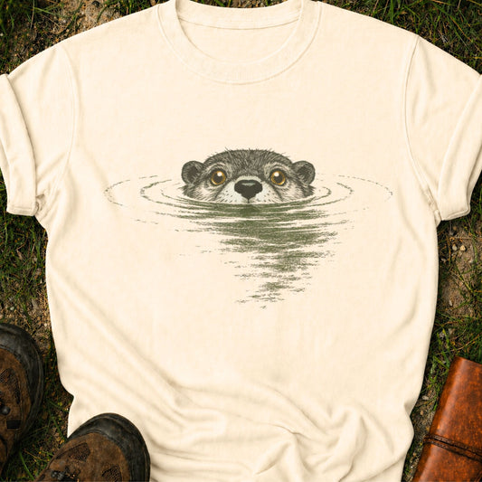 Ivory T-shirt with swimming otter design on lyimg on a grassy surface