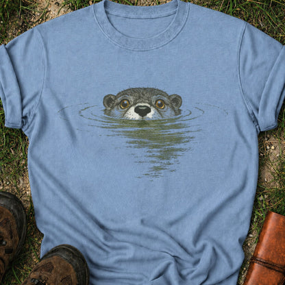 Blue T-shirt with swimming otter design on lyimg on a grassy surface