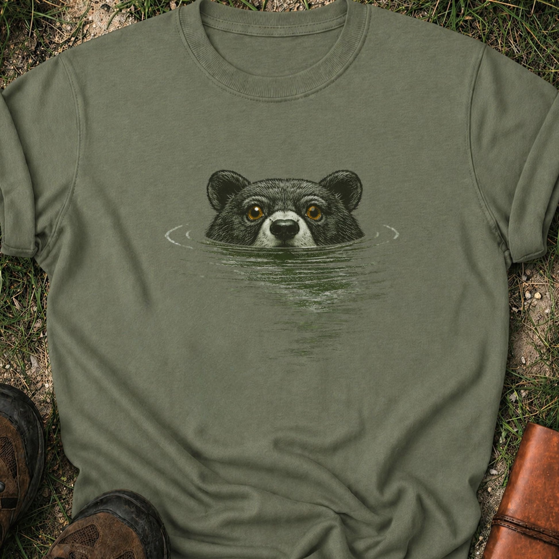 Moss Green t-shirt with a bear swimming graphic lying on a grassy surface