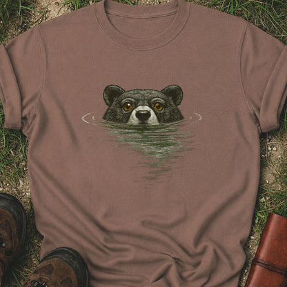 Brown T-shirt with a swimming bear  graphic lying on a grassy surface