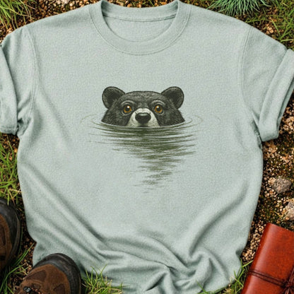 light green T-shirt with a swimming bear  graphic lying on a grassy surface