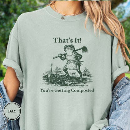 Model wearing a green T-shirt.  Graphic is a frog with a hand on his hip holding a hoe with the tagline "That's It!, You're Getting Composted.