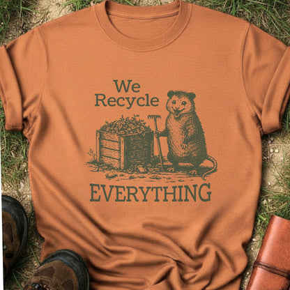 Orange T-Shirt  featyrubg a vintage-style opossum beside a compost bin with the bold phrase “We Recycle Everything.” 
