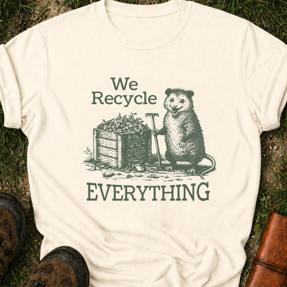 Ivory T-Shirt  featyrubg a vintage-style opossum beside a compost bin with the bold phrase “We Recycle Everything.” 