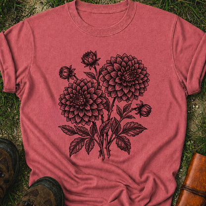 Dark Pink T-Shirt laying on a grassy surface.  The graphic features a minimal black botanical line art design featuring dahlias with leafy stems and delicate floral details.