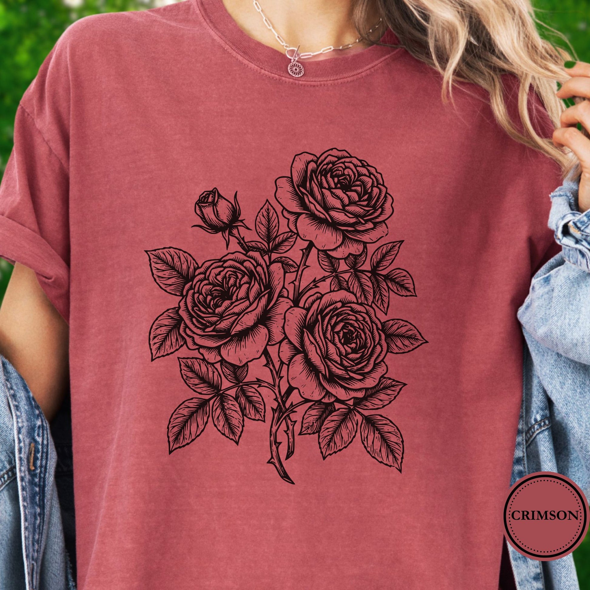 Model wears a Dark Pink Tshirt with a   Graphic showing a minimal black botanical line art design featuring elegant roses with leafy stems