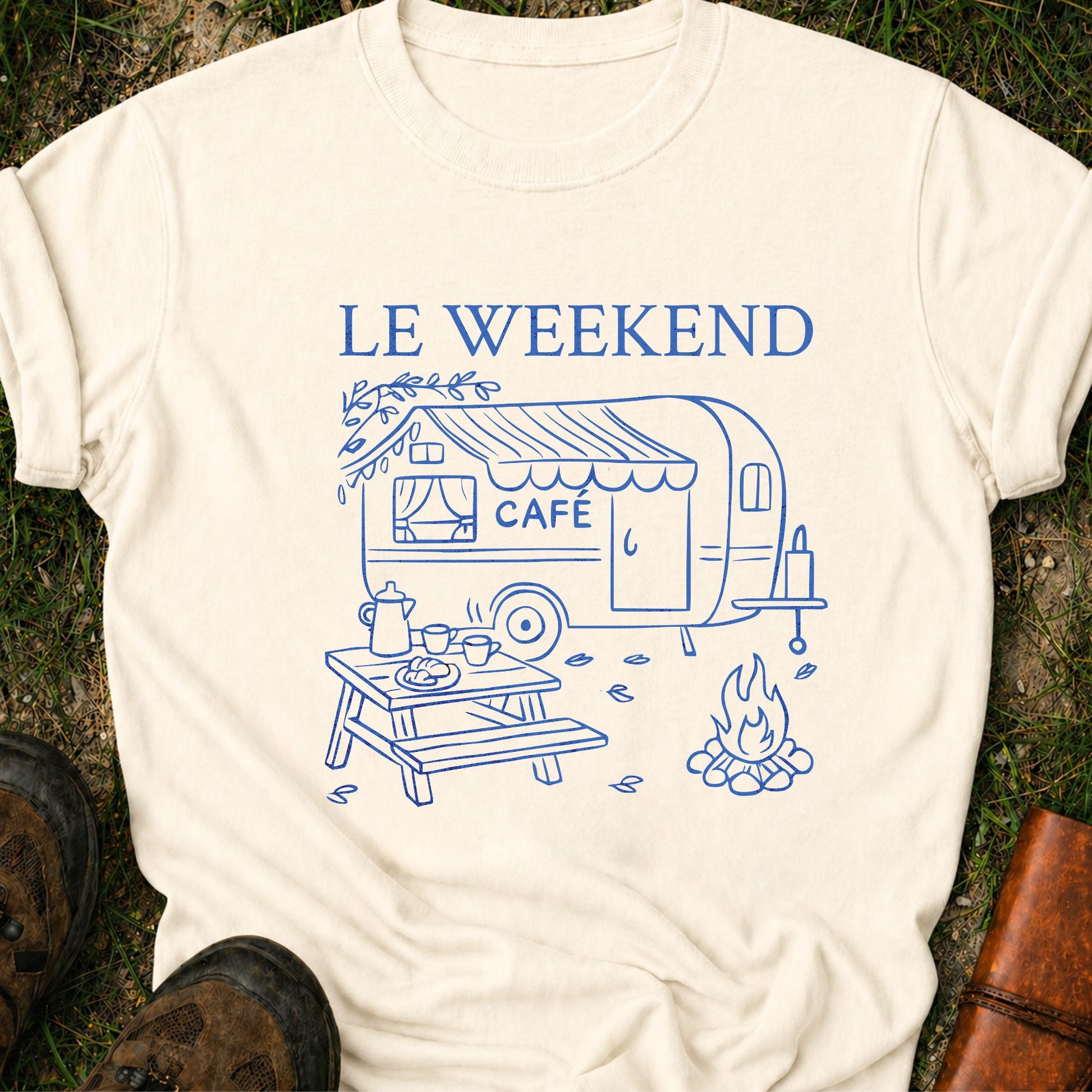 Ivory  t-shirt with blue graphic and 'LE WEEKEND CAFé' text on grass