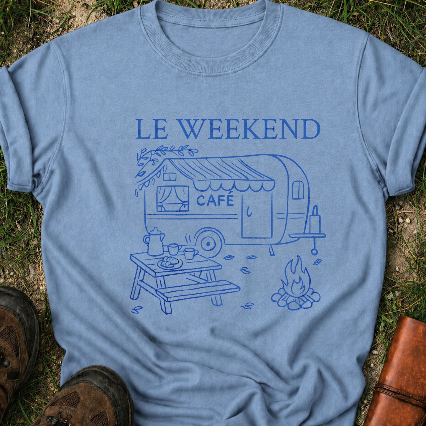 Blue t-shirt with 'Le Weekend Café' design on grass