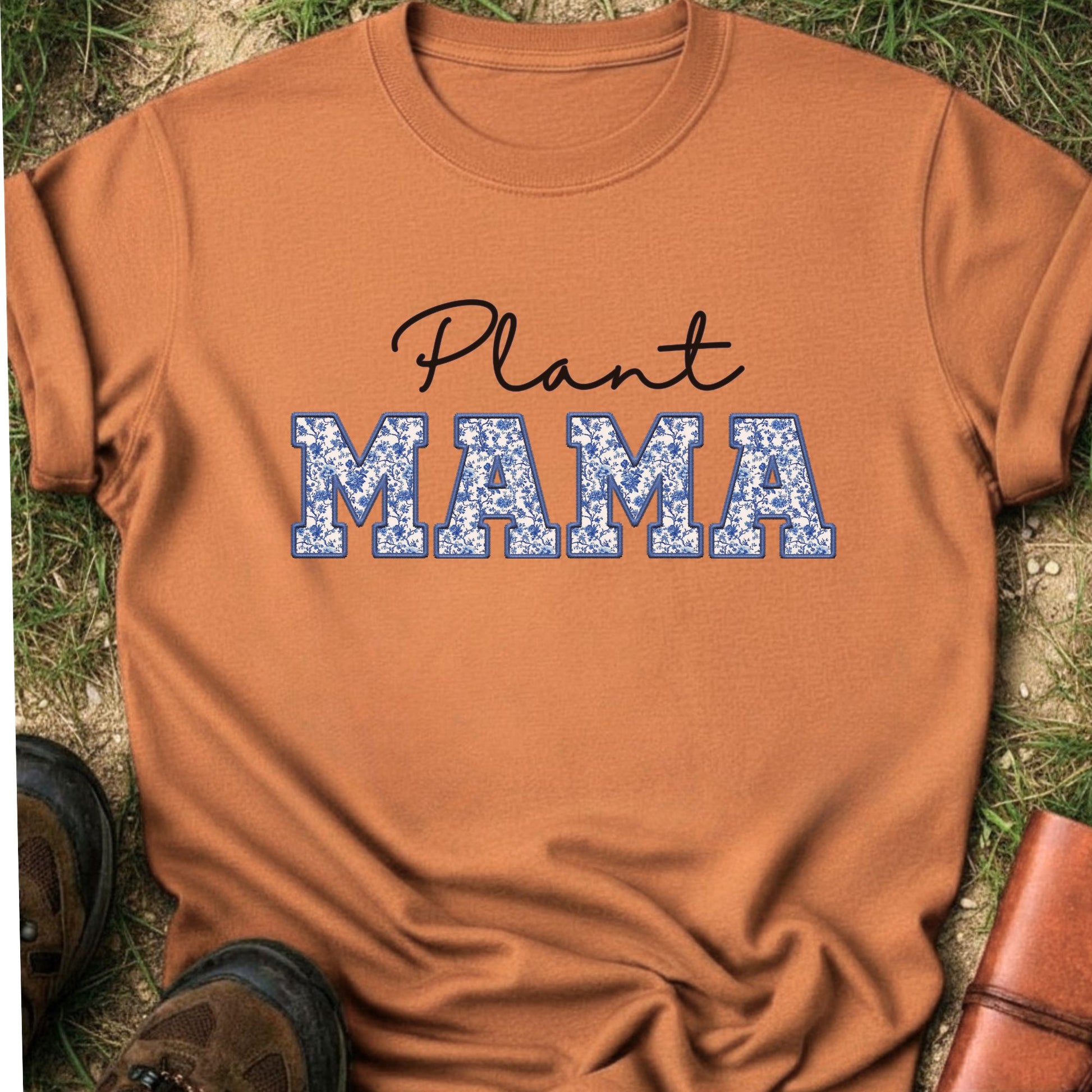 Orange t-shirt with 'Plant MAMA' text on a grass surface