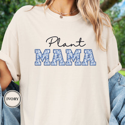 Model wears an ivory  t-shirt with 'Plant Mama' text on a blurred green background
