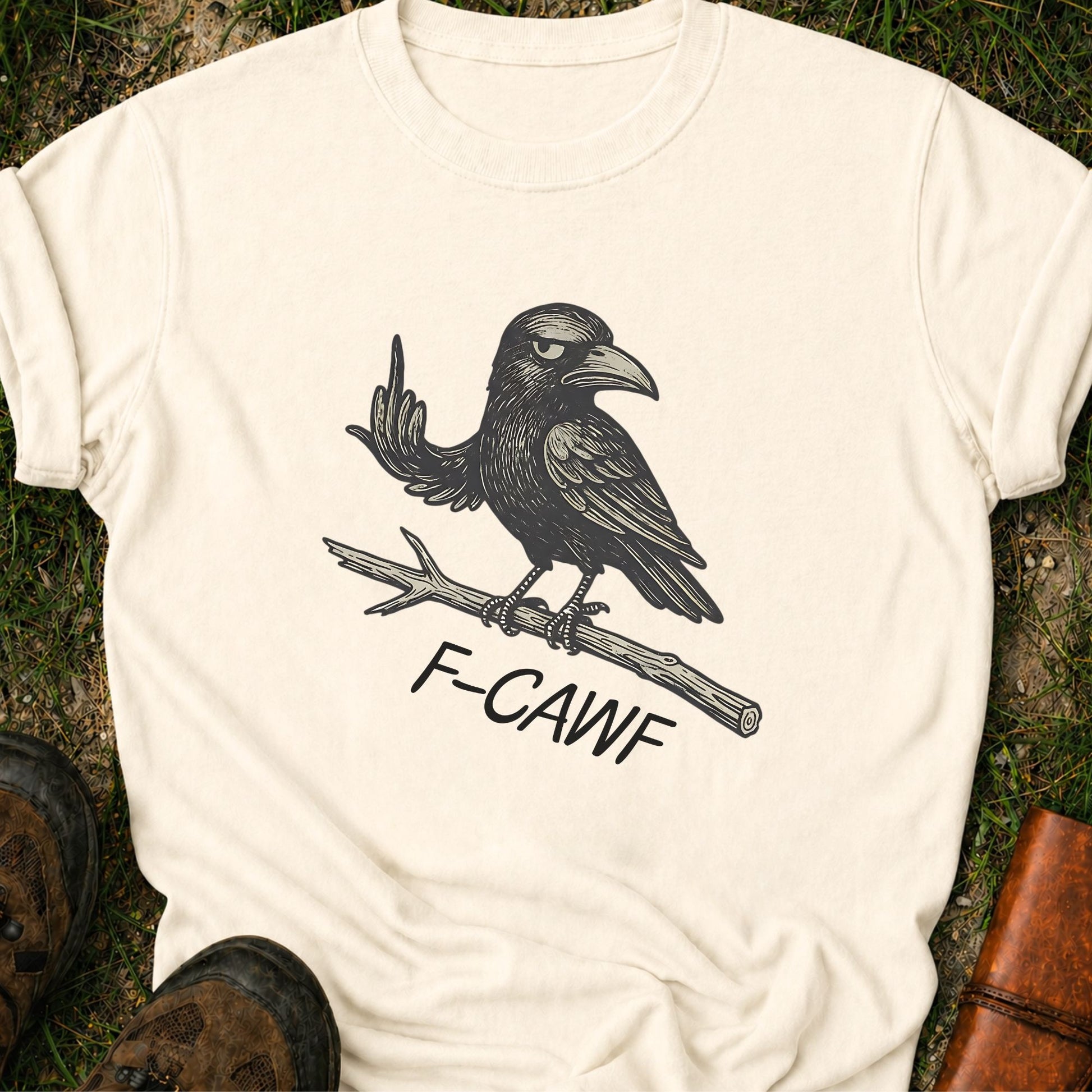 Ivory  t-shirt with a crow illustration makine a rude gesture with his wing and 'F-CAWF' text on a grass surface