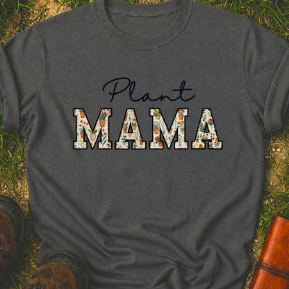 Gray t-shirt with 'Plant MAMA' text filled with cheerful potted plants and florals within the letters.  The tee is lying flat on grass