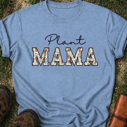 Bluet-shirt with 'Plant MAMA' text filled with cheerful potted plants and florals within the letters.  The tee is lying flat on grass