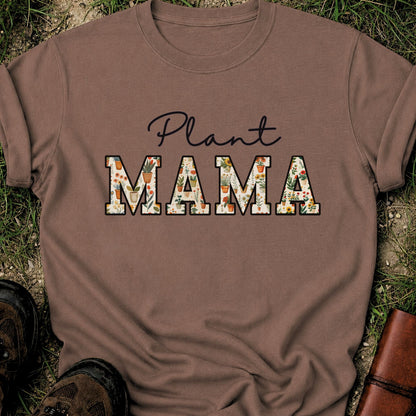 Brown t-shirt with 'Plant MAMA' text filled with cheerful potted plants and florals within the letters.  The tee is lying flat on grass