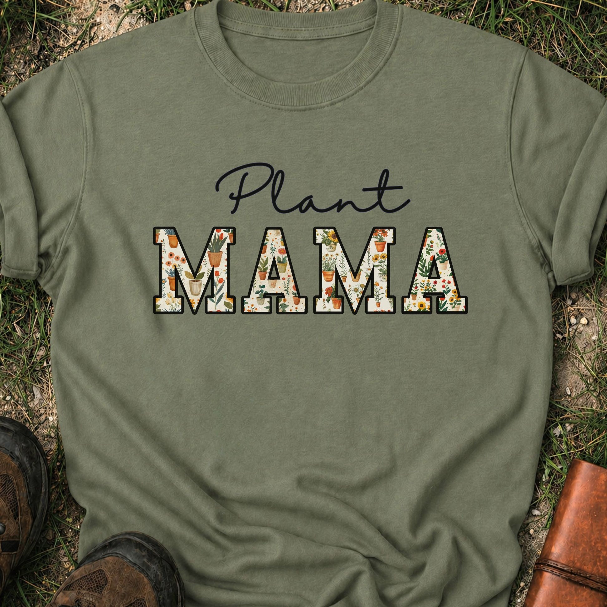 Green t-shirt with 'Plant MAMA' text filled with cheerful potted plants and florals within the letters.  The tee is lying flat on grass