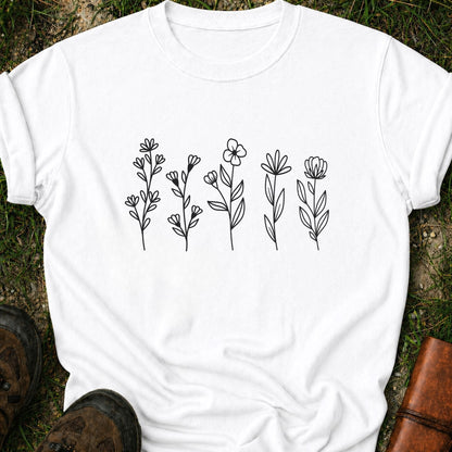 White t-shirt with black floral designs on grass