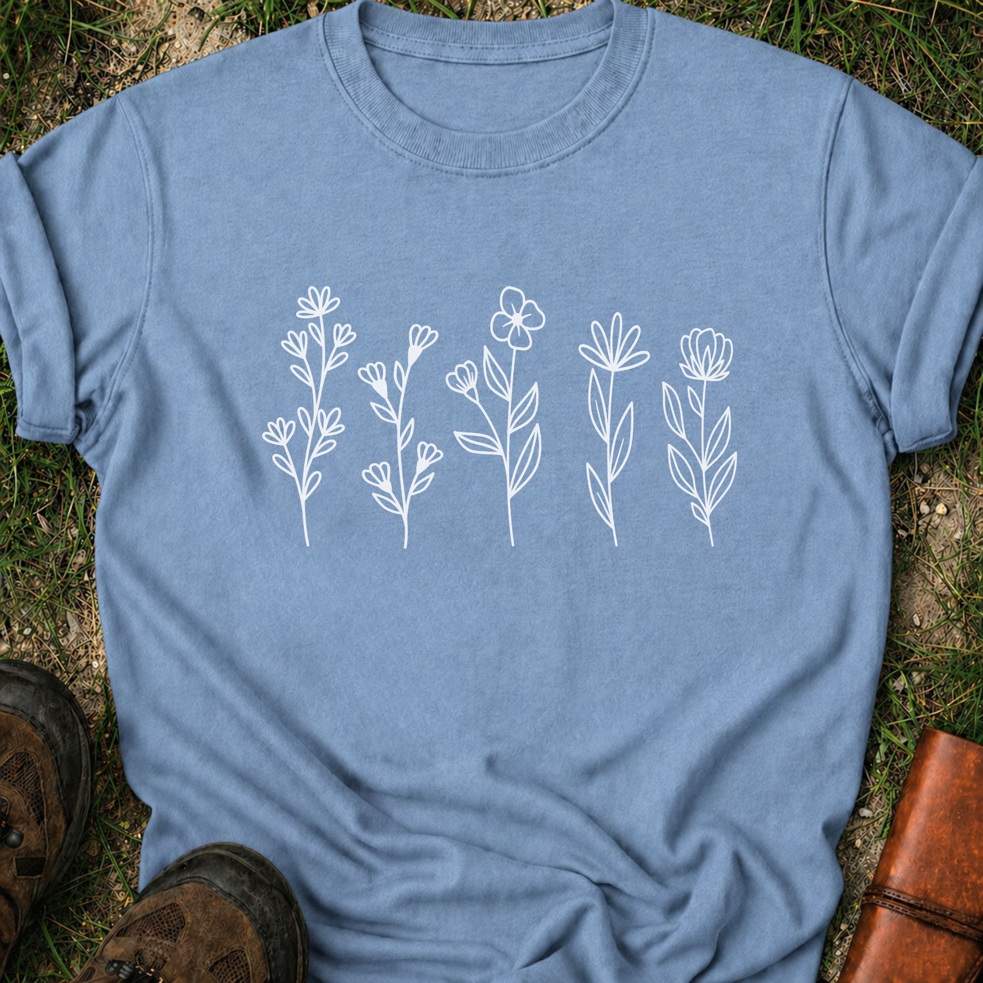 Blue t-shirt with white floral designs on grass