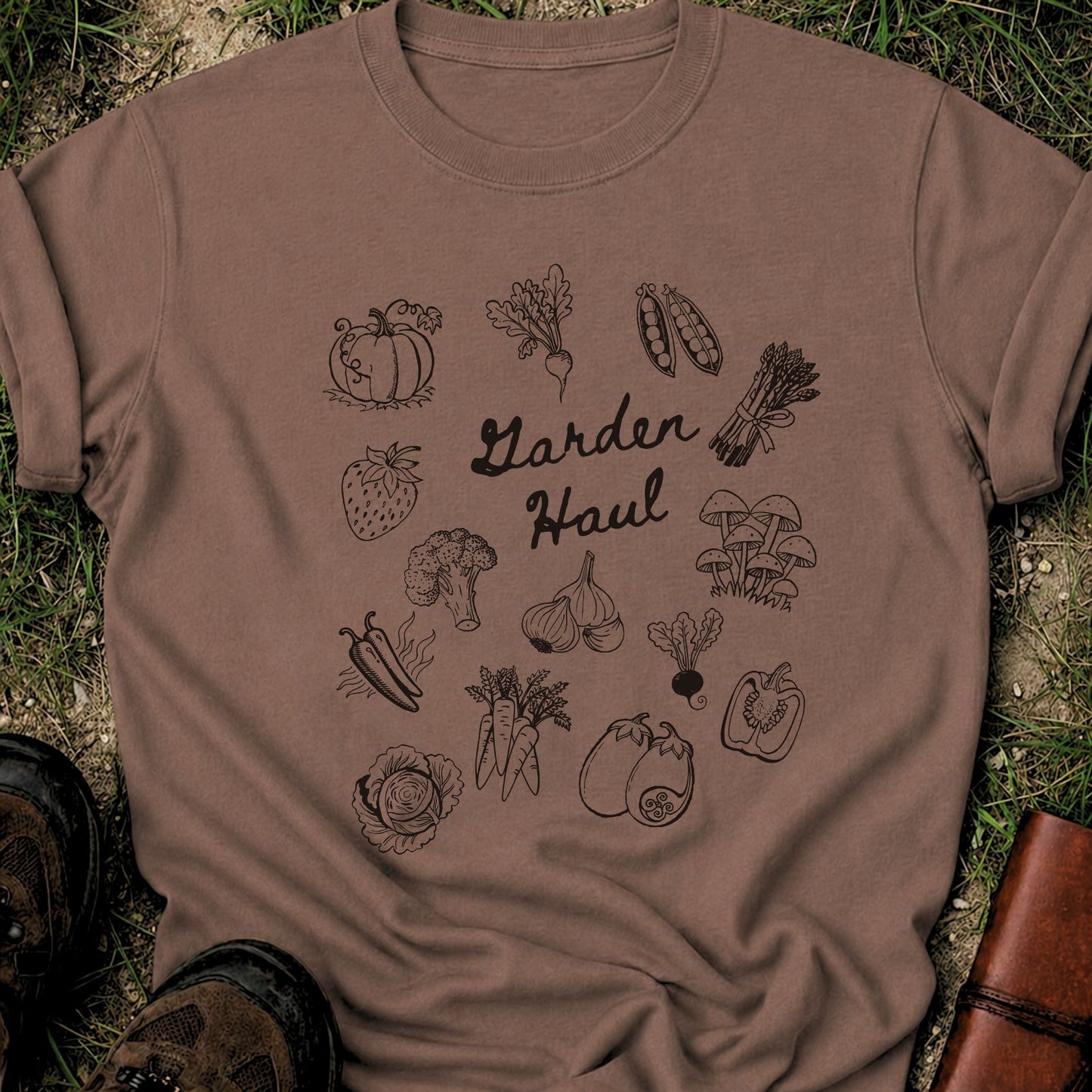 Brown t-shirt with garden-themed illustrations and the tgline Garden Haul on grass