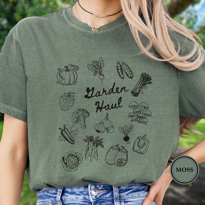 Person wearing a green t-shirt with vegetable illustrations and 'Garden Haul' text, standing outdoors.