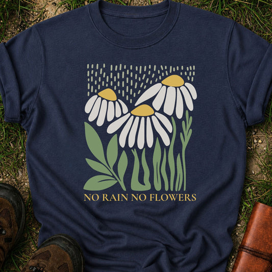 Navy blue T-Shirt with 3 boho style flowers in the rain with the text "No Rain No Flowers".  Tshirt is lying flat on grass.