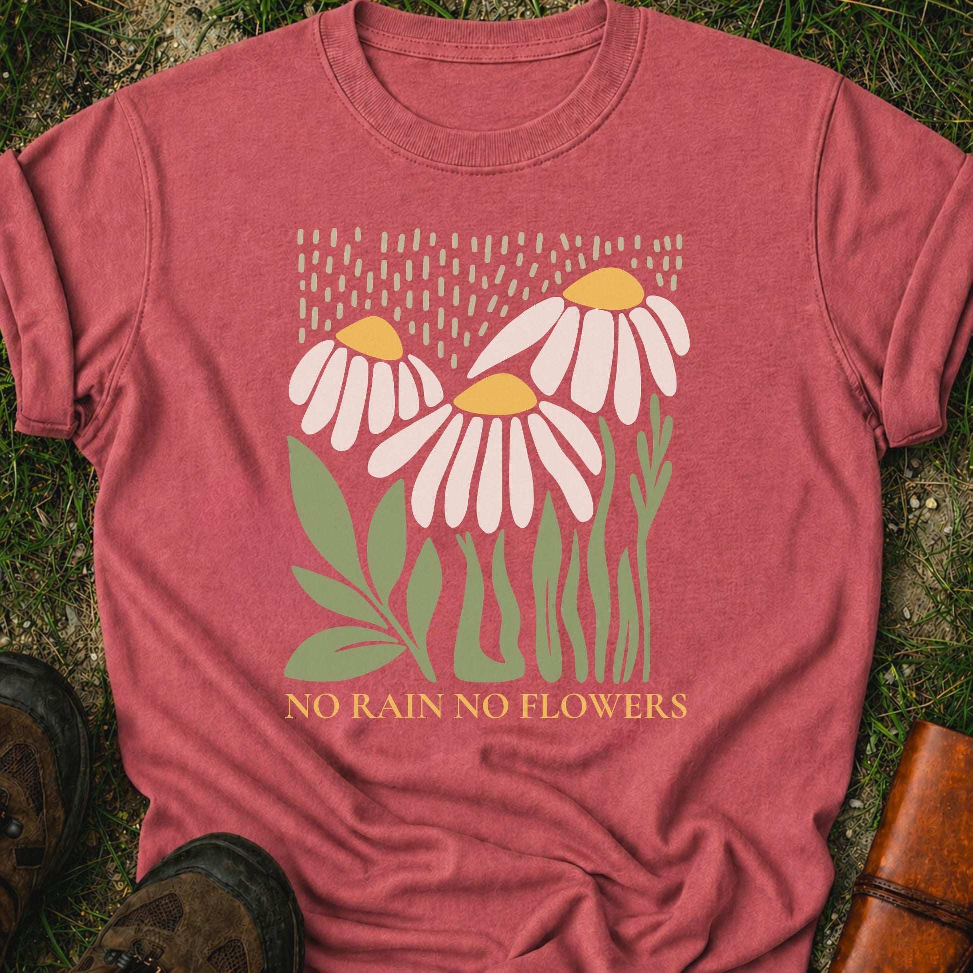 Dark Pink T-Shirt with 3 boho style flowers in the rain with the text "No Rain No Flowers".  Tshirt is lying flat on grass.