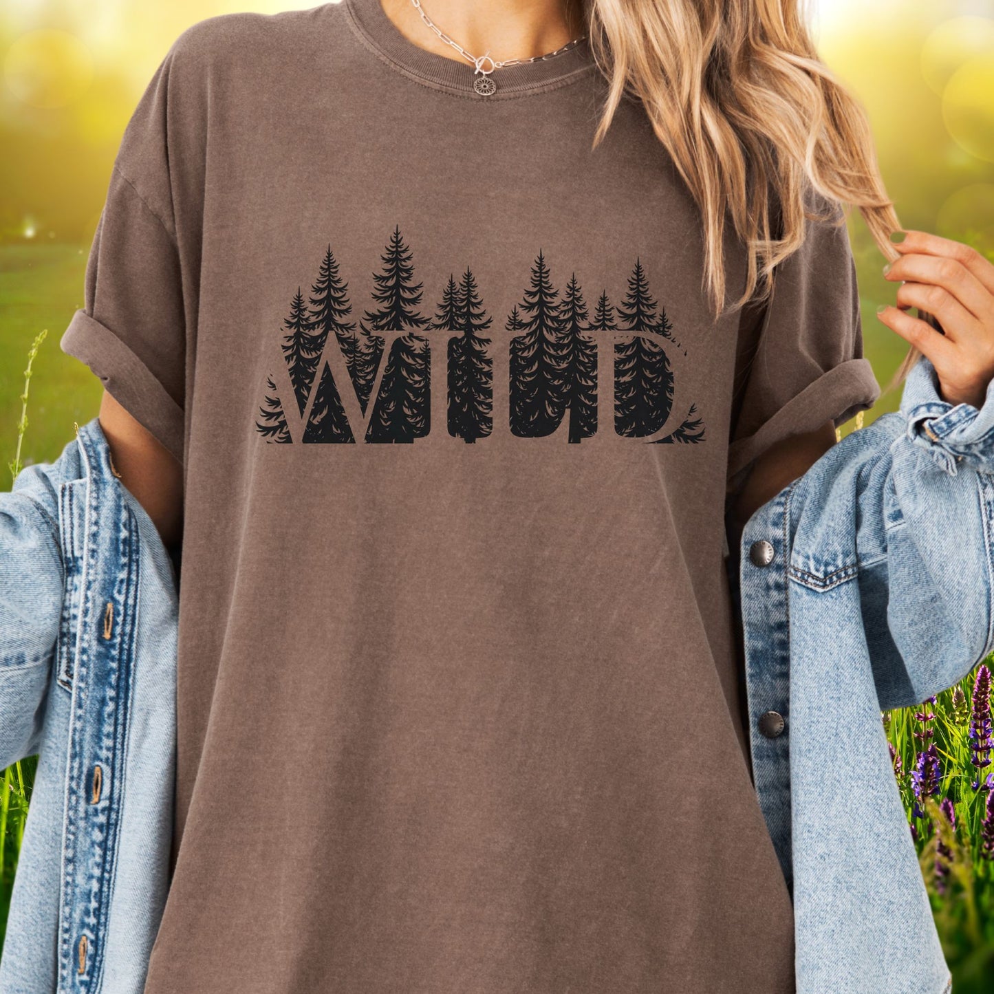 Model wears a brown t-shirt with the word WILD cut into a  forest design.