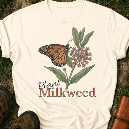 Ivory t-shirt with a butterfly and milkweed design  and the caption Plant Milkweed lying  on the grass