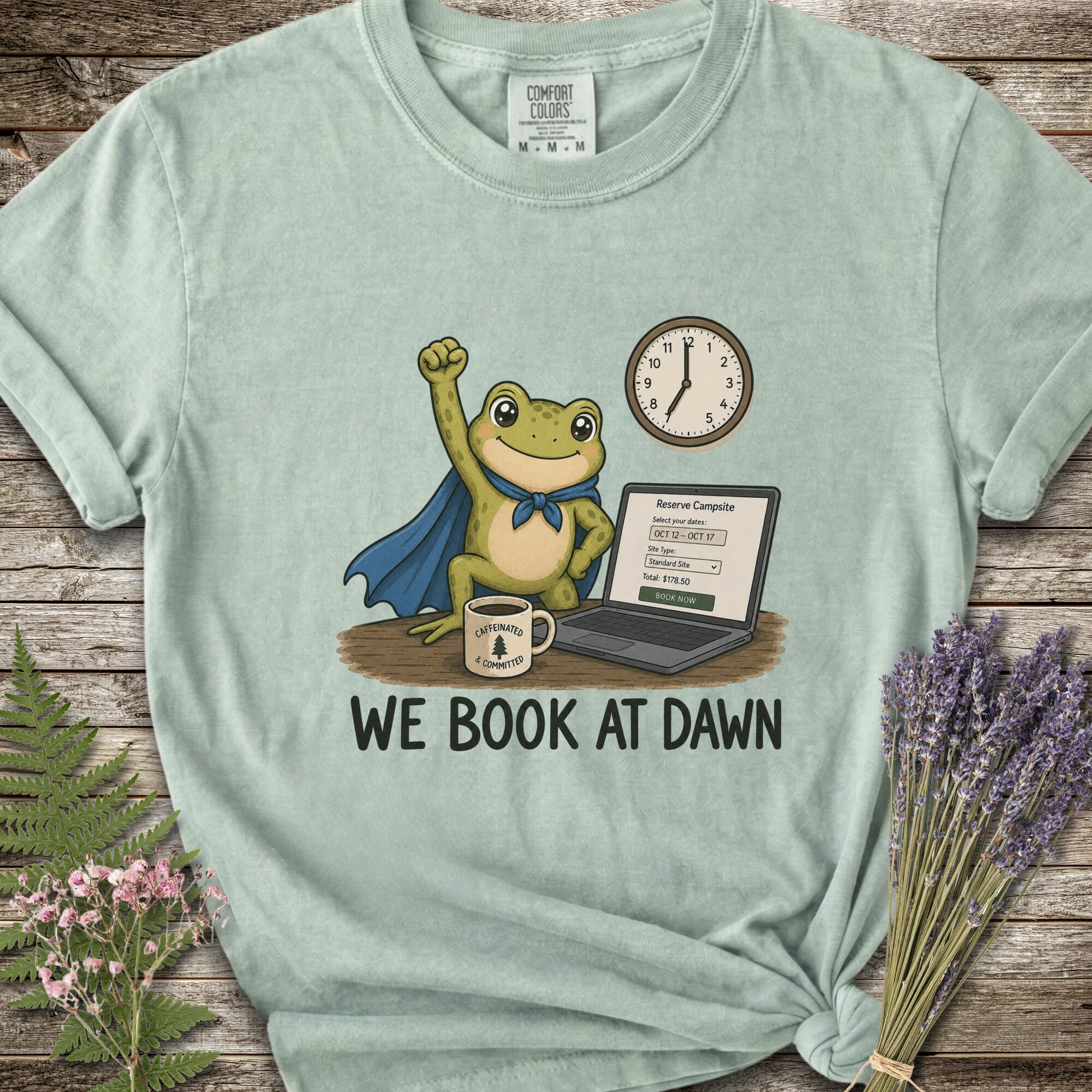 Light Green T-shirt with the image of a frod with his fist raised in front of a computer with the phrase "We Book At Dawn"
