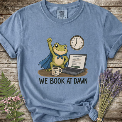 Blue T-shirt with the image of a frod with his fist raised in front of a computer with the phrase "We Book At Dawn"