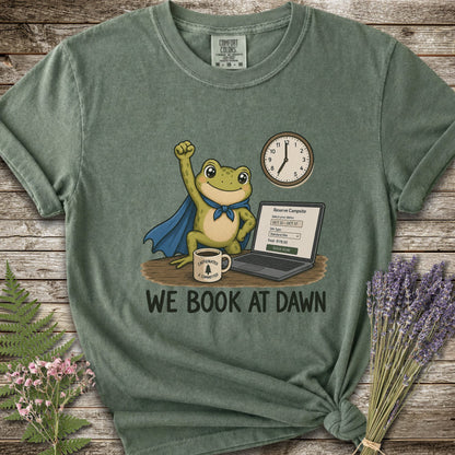 Moss Green T-shirt with the image of a frod with his fist raised in front of a computer with the phrase "We Book At Dawn"