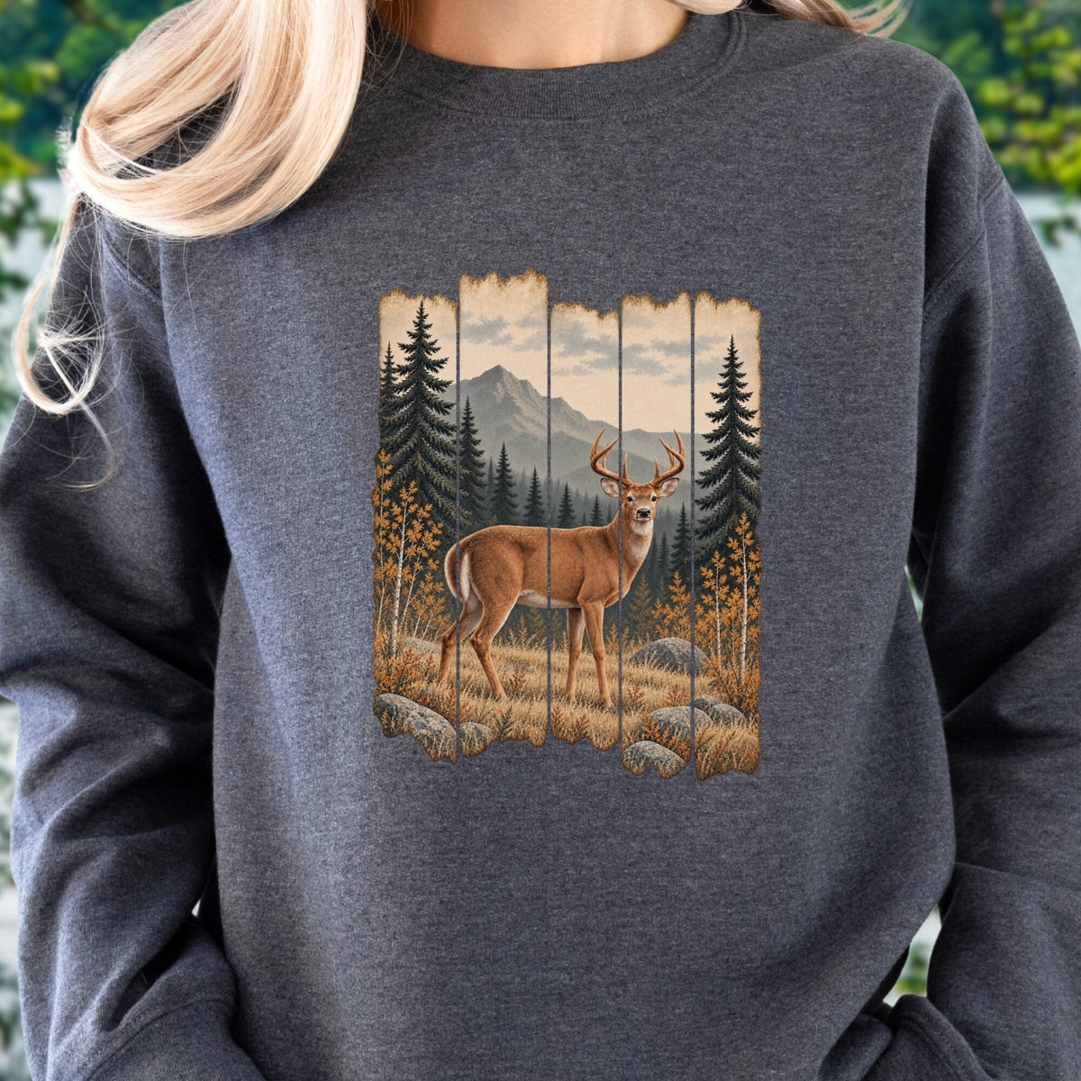 A person wearing a dark heather gray crewneck sweatshirt with a large graphic print of a deer in a forest on the front.