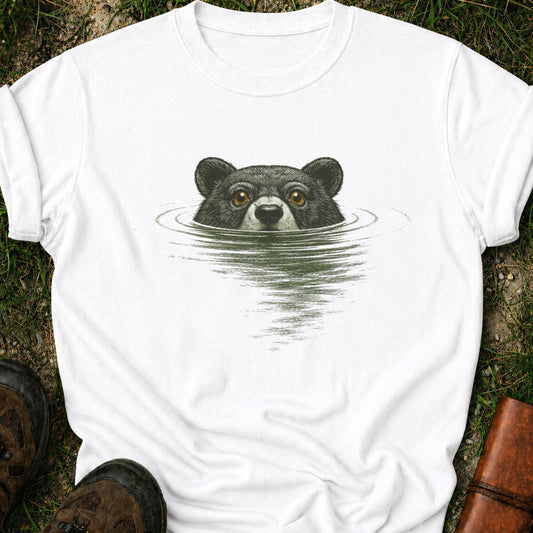 White T-shirt with a swimming bear  graphic lying on a grassy surface