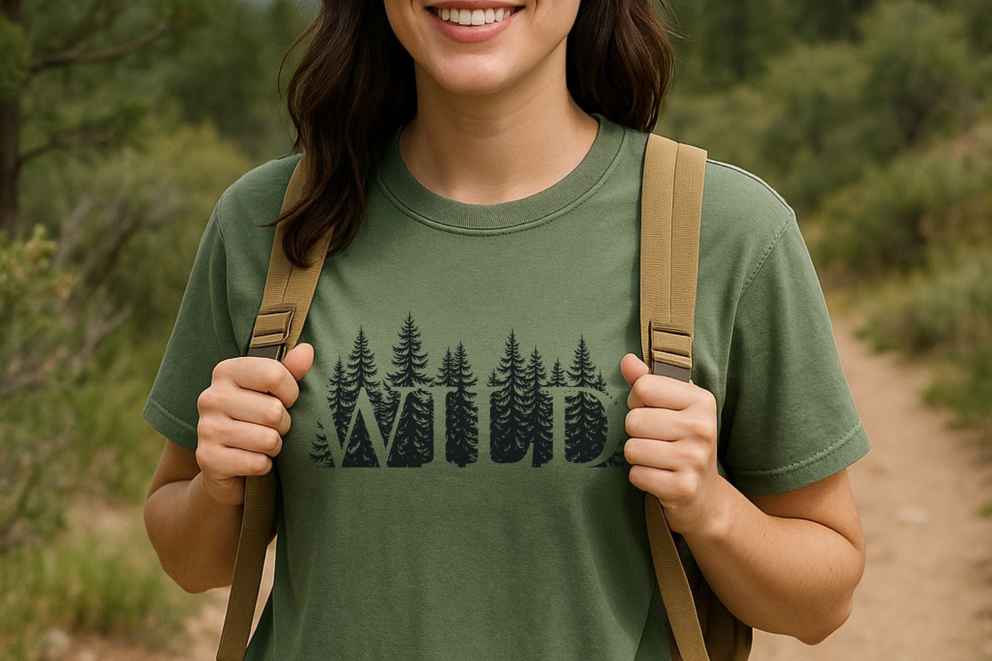 Person wearing a green t-shirt with a forest design, standing on a trail in a natural setting.